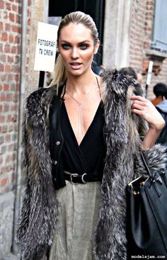 a woman is walking down the street wearing a fur coat