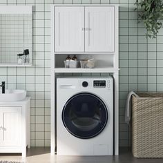 a washer and dryer in a bathroom with green tiles on the wall, next to a white cabinet