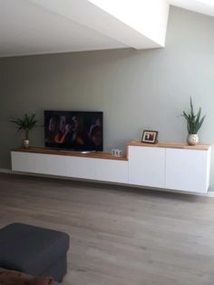 a flat screen tv sitting on top of a white entertainment center in a living room