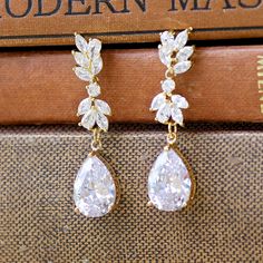 "Glamorous Gold Crystal Earrings in a teardrop style will add sweet sparkle to your wedding day. Marquise zircon crystals in a double leafy design are completed with a Swarovski crystal teardrop. Comfortable, light, and very sassy - they are a beautiful mid length earring. Annie is perfect for the elegant bride. Length : approx 1.25\" (3.2 cm) Nickel free & allergy free posts. High quality cubic zircons set in 18K gold plate. 💜 Available in rose gold, silver (rhodium) and gold 💟 Items that Gold Sparkling Crystal Earrings For Wedding, Dazzling Gold Teardrop Bridal Earrings, Gold Sparkling Cubic Zirconia Teardrop Earrings, Gold Nickel-free Crystal Earrings For Wedding, Gold Pear-shaped Cubic Zirconia Bridal Earrings, Bridal Earrings Chandelier, Gold Earrings Wedding, Elegant Bride, Gold Wedding