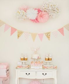 a table topped with cake and cupcakes on top of a white dresser next to a wall