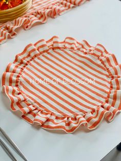 an orange and white striped paper plate sitting on top of a table next to a basket