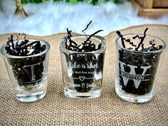 three shot glasses filled with black beads on top of a table