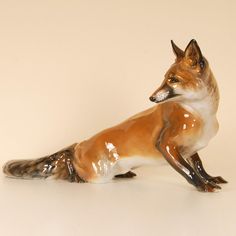 a ceramic figurine of a fox sitting on the ground