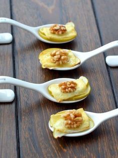 four spoons filled with food sitting on top of a wooden table