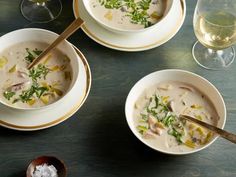 three bowls of soup are sitting on a table with wine glasses and utensils