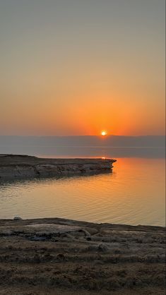 the sun is setting over the water and there are boats out on the water in the distance