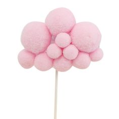 a close up of a pink cotton candy on a stick with pom - poms