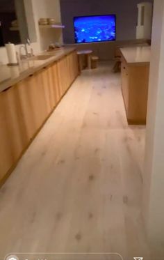 an empty kitchen with wooden cabinets and a large screen tv on the wall behind it