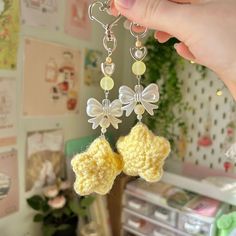 a person is holding up a crocheted keychain with two bows on it