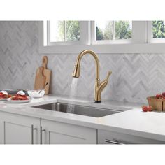 a kitchen sink with a faucet and cutting board on the counter next to it