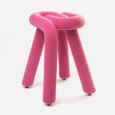 a pink stool that is sitting on top of a white surface with black feet and legs