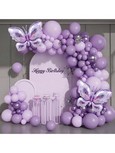 a purple birthday decoration with balloons and butterflies on the front, next to a white plaque that says happy birthday