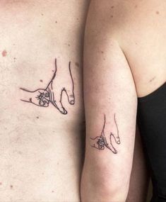 two people with tattoos on their stomachs are holding each other's hands together