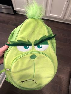 the grin face backpack is being held up to show it's green hair and eyes