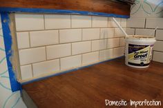 a bucket of paint sitting on top of a wooden counter next to a brick wall