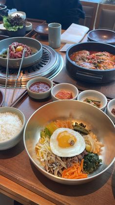 a wooden table topped with bowls filled with food