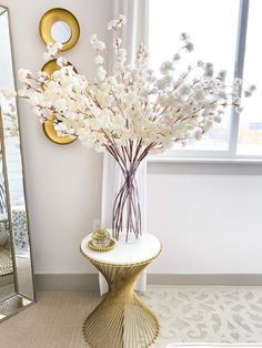 a vase filled with white flowers sitting on top of a table next to a mirror