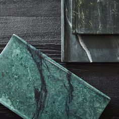 a green marble plate sitting on top of a wooden table next to a metal box