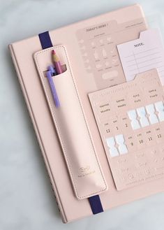 a pink planner and pen on a table