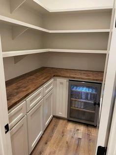 an empty kitchen with white cabinets and wood counter tops on the bottom half of the room