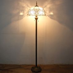 a lamp that is on top of a wooden floor next to a wall with a shadow cast on it