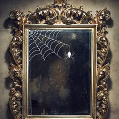 a gold framed mirror with a spider web on it