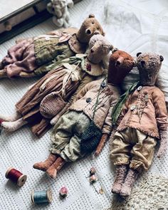 two old dolls laying on the floor next to thread spools