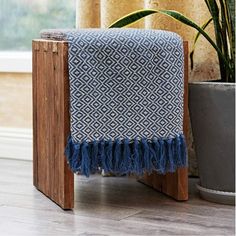 a blue and white blanket sitting on top of a wooden stand next to a potted plant