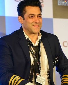 a man in a suit and tie sitting at a table with his hands on his hips