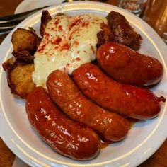 a white plate topped with sausages and potatoes