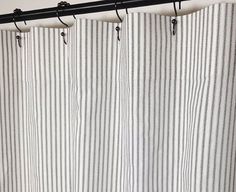 a white and black striped shower curtain hanging from a metal rod in front of a wall