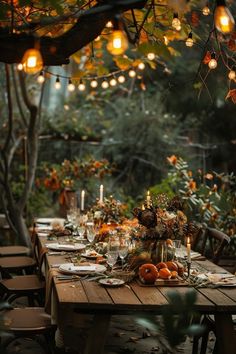 an outdoor dinner table set up with candles, flowers and pumpkins on the table