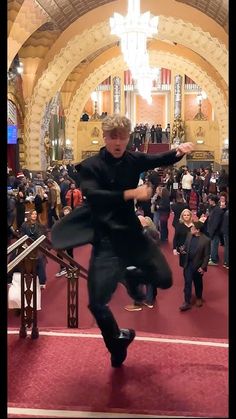 a man is dancing in front of a large crowd at a church with his arms outstretched