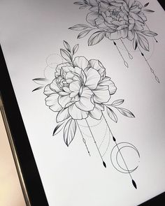 a black and white drawing of flowers on a sheet of paper next to a pen