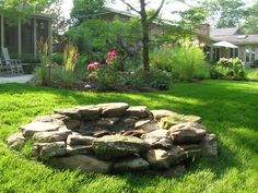 a stone fire pit in the middle of a lawn