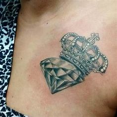 a woman's chest with a crown and diamond tattoo on her left side breast