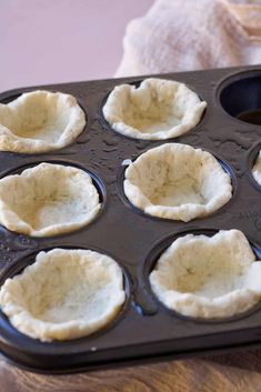 an uncooked muffin tin with six cupcakes in it on a wooden table