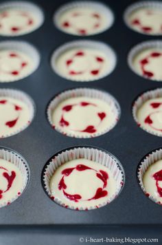 cupcakes with white and red icing in a muffin tin