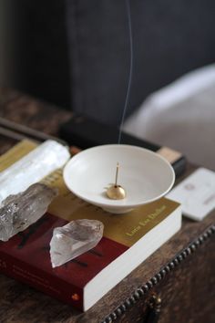 a white bowl sitting on top of a table next to a book and some rocks