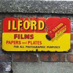 a sign on the side of a brick wall advertising films and plates for all photographic purposes