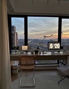 a room with a desk, chair and large window looking out at the city outside