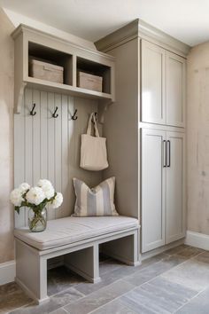 a white bench sitting next to a wooden shelf filled with bags and flowers on top of it