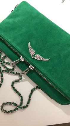 a green purse sitting on top of a white table next to a chain and key