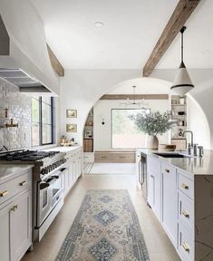 a large kitchen with white cabinets and an area rug on the floor in front of the stove