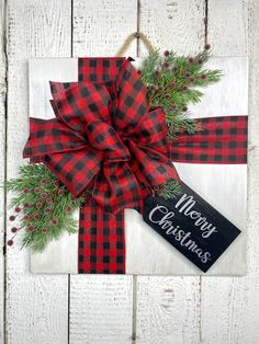 a christmas present wrapped in red and black plaid ribbon with a merry christmas tag hanging on it