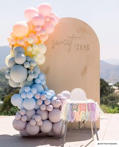 a table with balloons and a sign on the side that says sweet one next to it