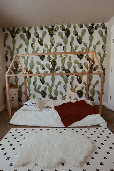 a bedroom with cactus wallpaper and a white bed in front of a wooden headboard