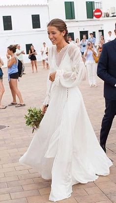 a woman in a white dress is walking with a man wearing a suit and tie