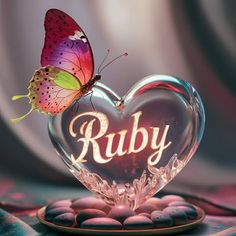 a butterfly sitting on top of a heart shaped object with the word ruby in it